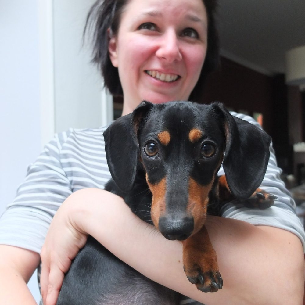 Brenda, zaakvoerder van The Pup Hub Leuven, met haar teckel op de arm
